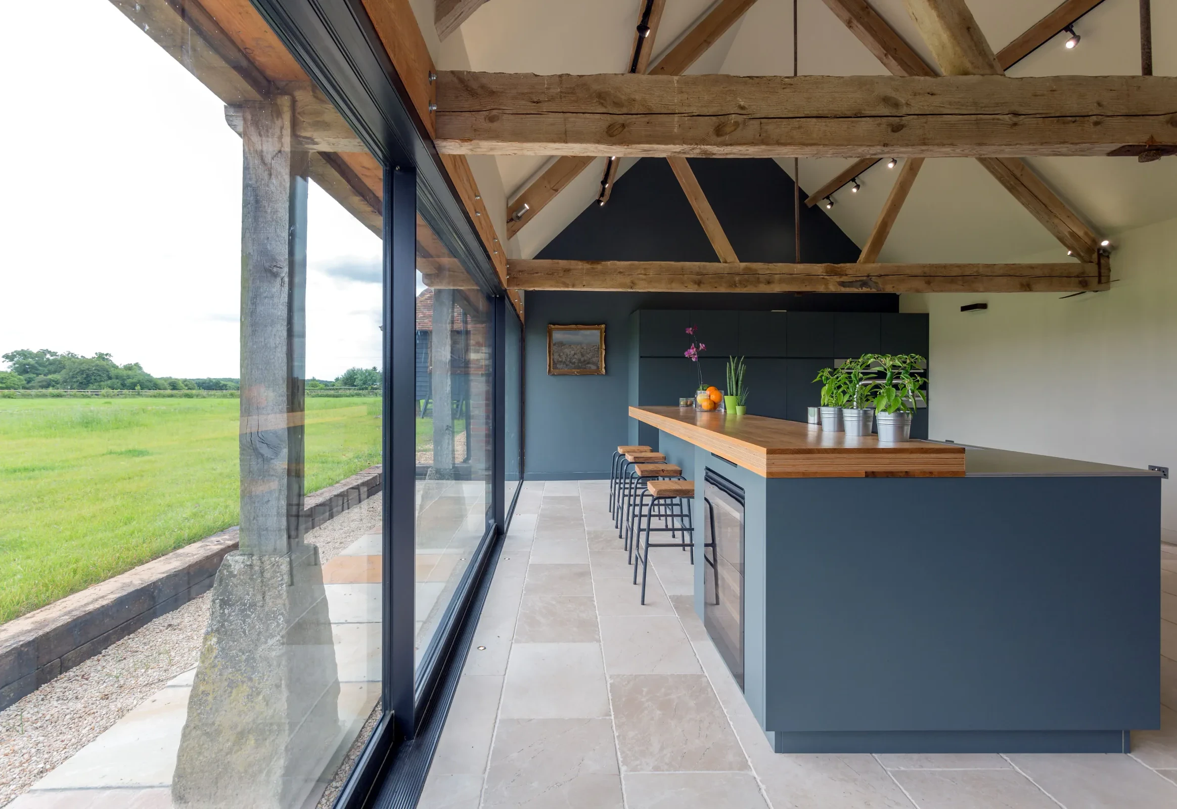 Farmhouse — an open kitchen under exposed timber trusses with views across the fields