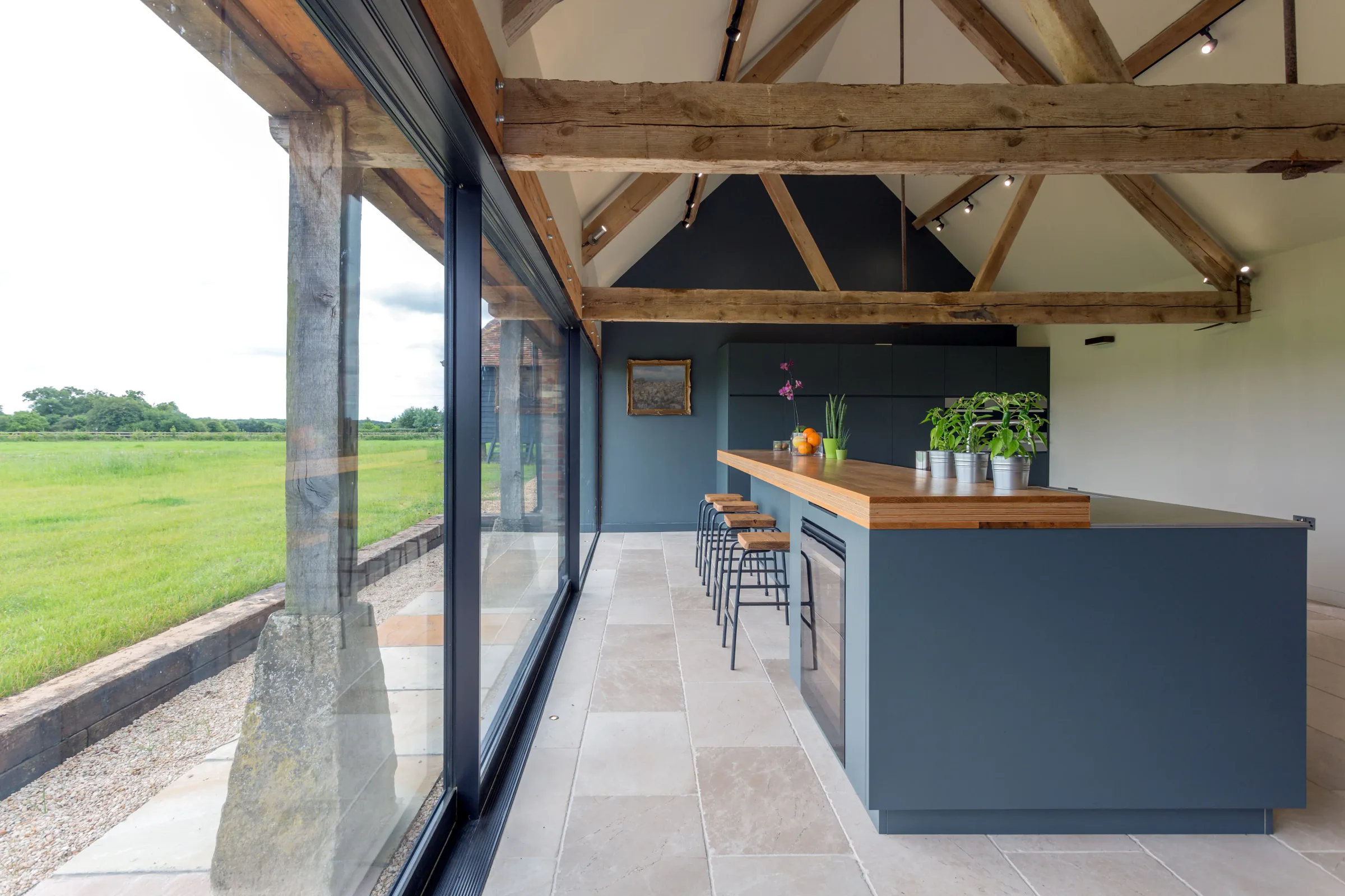 Farmhouse — an open kitchen under exposed timber trusses with views across the fields